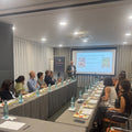 Dimitri Anastopoulos de pie realizando una cata privada en grupo en formación de mesas en sala de. hotel con pantalla, vasitos con aceite y maridajes