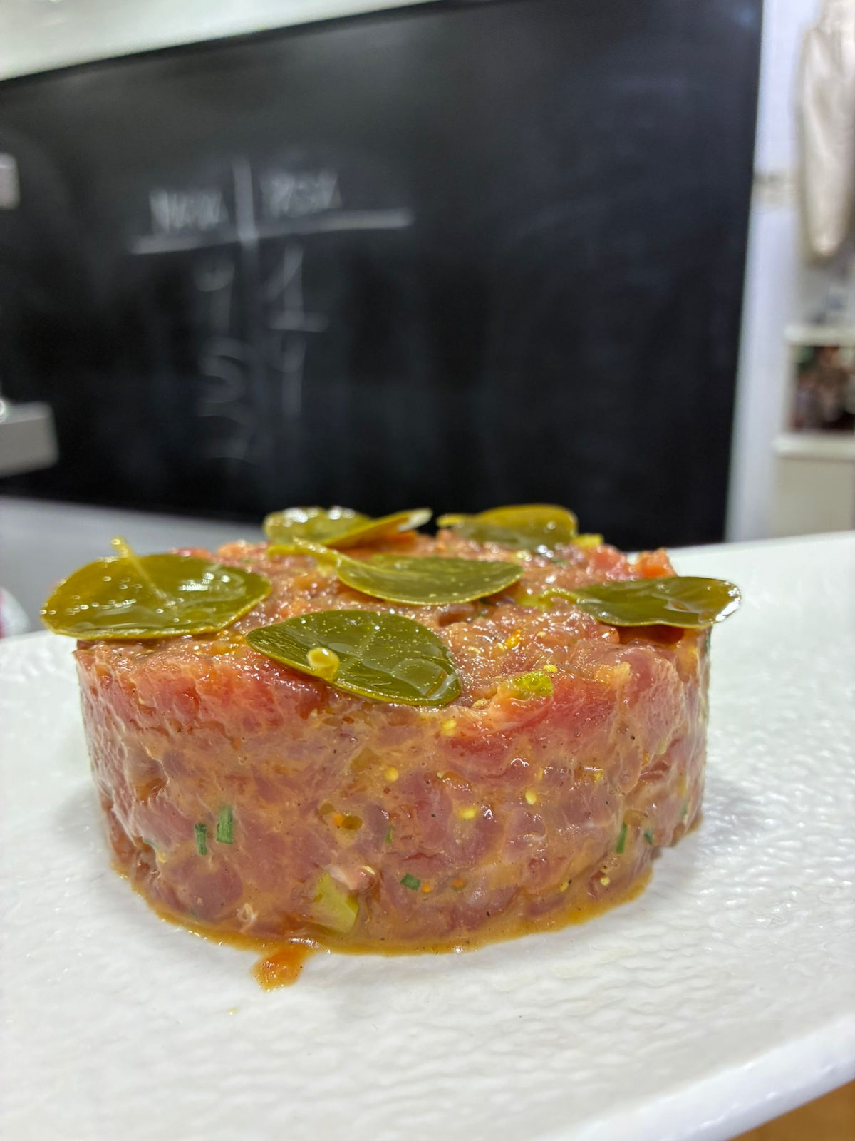Tartare gastronomique garni de feuilles de câprier grecques et herbes fraîches