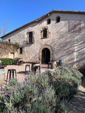 Façade de la Masia Can Calopa avec sa cour et ses plantes aromatiques.